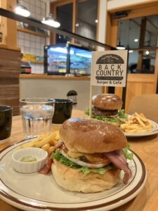 リゾナーレ小淵沢のすぐ近くにあるハンバーガーSHOP「BACK COUNTRY Burger＆Cafe」のハンバーガーの画像。ボリューム満タンでポテトとピクルス付き。