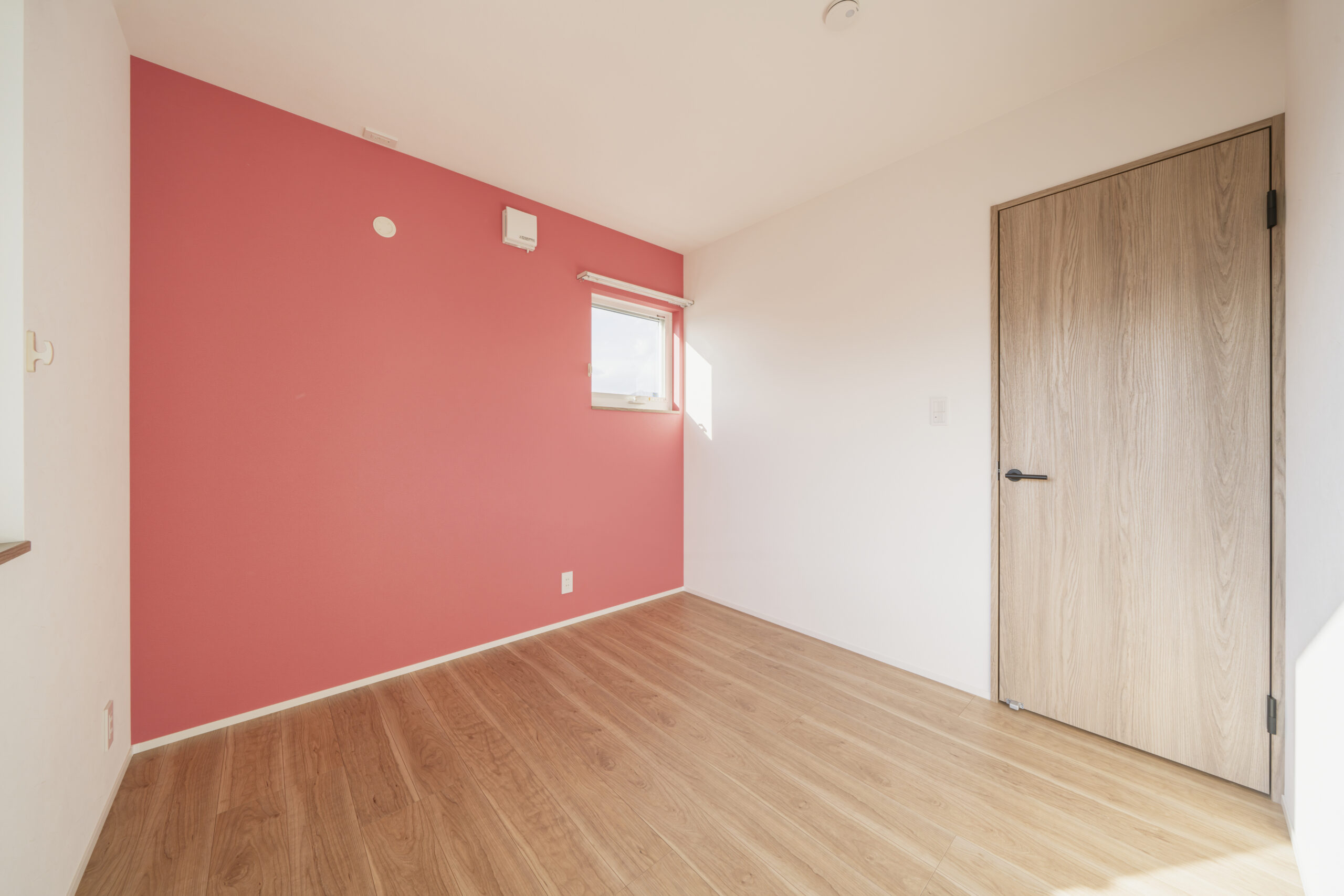 鮮やかなアクセントカラーの壁に温もりのある床の部屋には自然光がよく照らしてくれます。