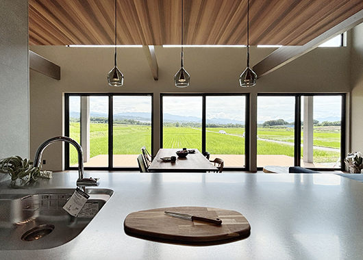 甲斐市の平屋施工事例。キッチンからリビングの大きな窓を通して、外の水田風景が見えます。