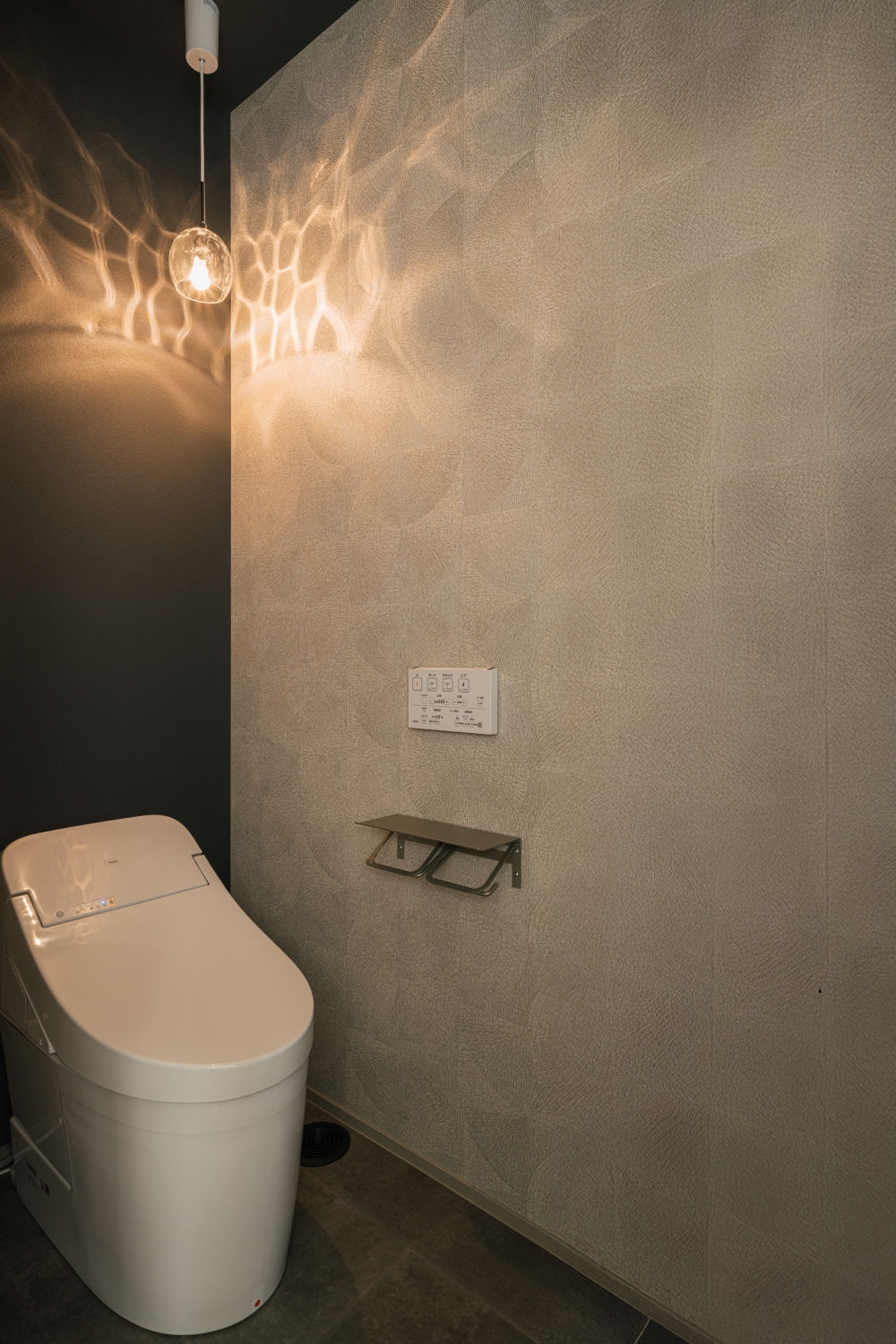 グレーの壁と照明が印象的なトイレ。落ち着きとデザイン性を両立。