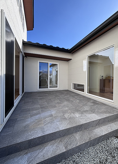 タイルデッキを採用した中庭。室内とつながるコの字型平屋の屋外スペース。